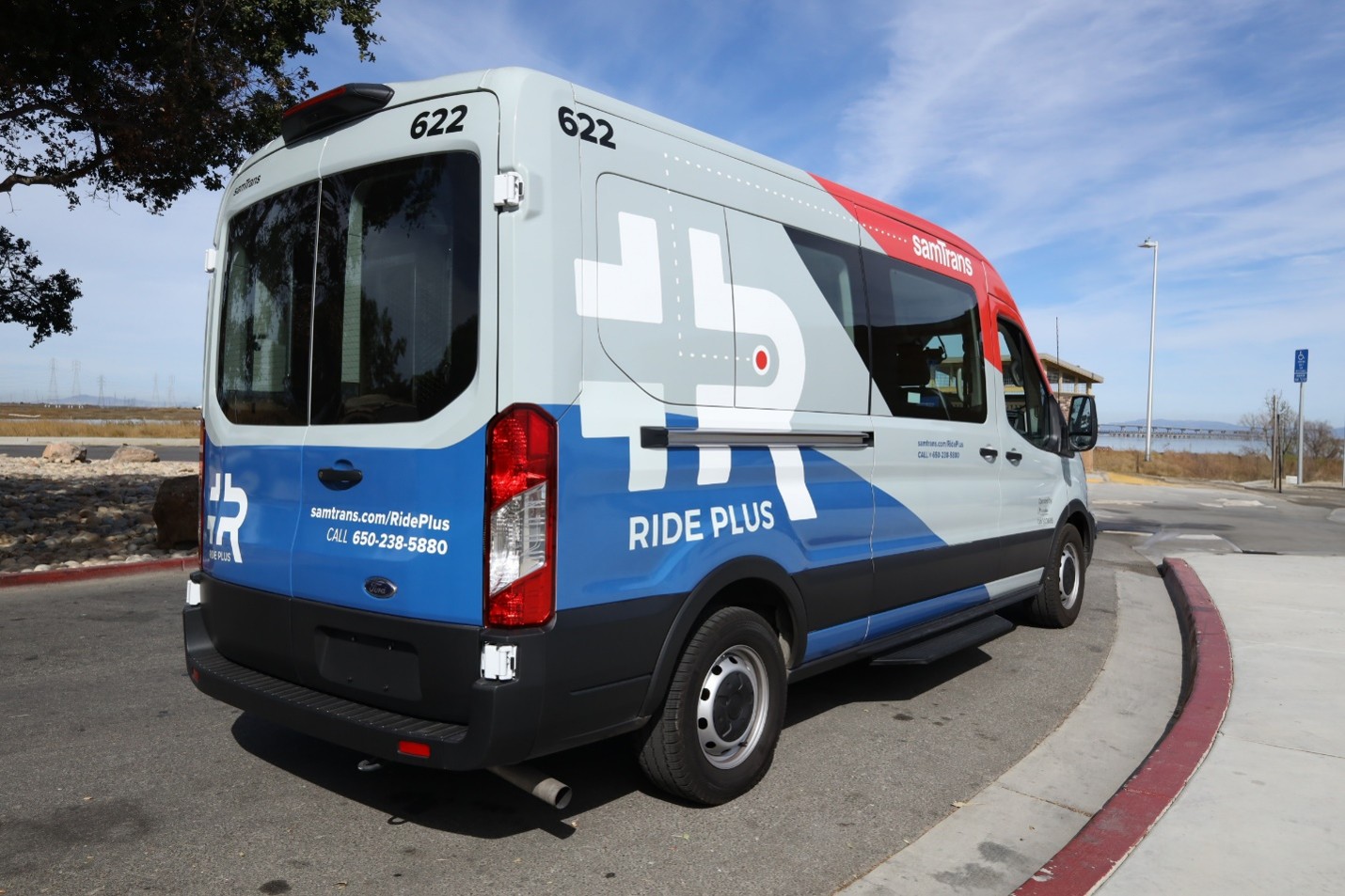 Child riding in a replica SamTrans bus next to a real SamTrans bus